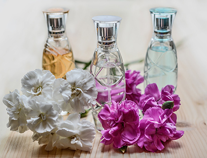 Parfymflaskor med blommor på träbakgrund